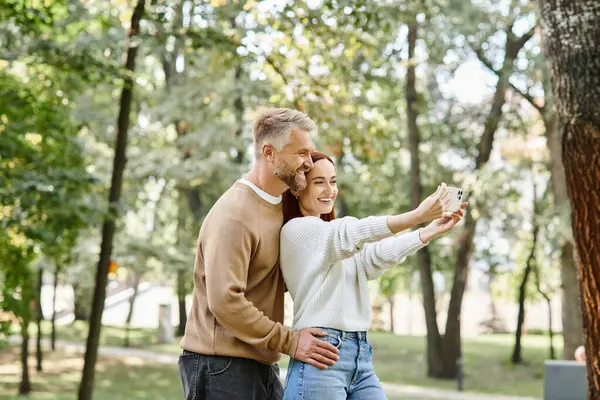 Un couple amoureux capture un moment dans le parc alors qu'ils prennent un selfie ensemble. — Photo de stock