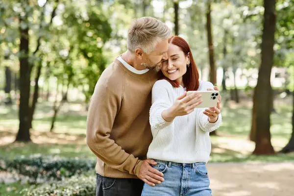 A man and woman in casual attire engaged with a cell phone. — Stock Photo