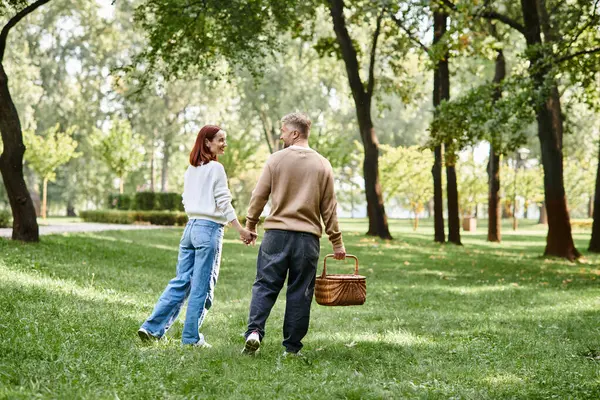 A couple, man and woman, hold hands while walking through a peaceful park. — Stock Photo