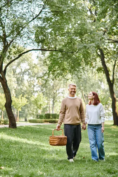A man and woman enjoying a romantic walk through a park holding hands. — Stock Photo
