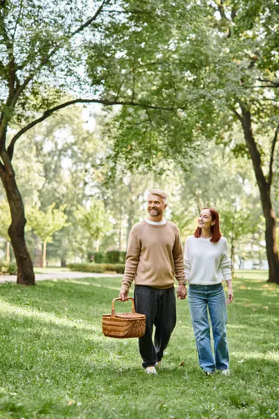 A couple, casually dressed, peacefully walking through a park. — Stock Photo