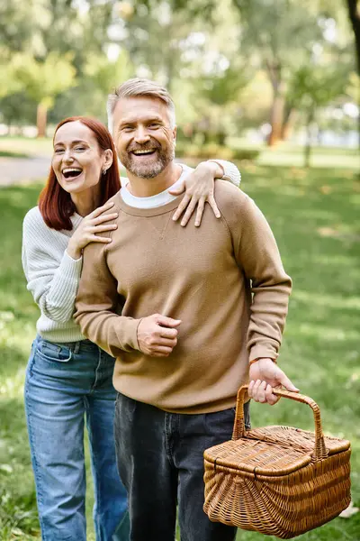 A man and a woman in casual attire are enjoying a leisurely walk through a serene park. - foto de stock