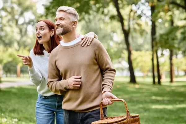 A loving couple in casual attire embraces amidst lush greenery in a serene park setting. — Stock Photo