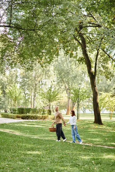 A loving couple, casually dressed, walks through a peaceful park. — Stock Photo