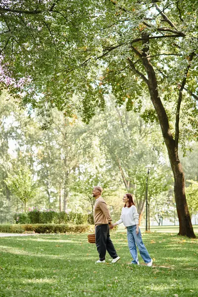 Una pareja adulta cariñosa camina pacíficamente por un parque. - foto de stock