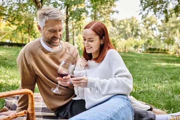 Casal gosta de vinho em cobertor no parque. — Fotografia de Stock