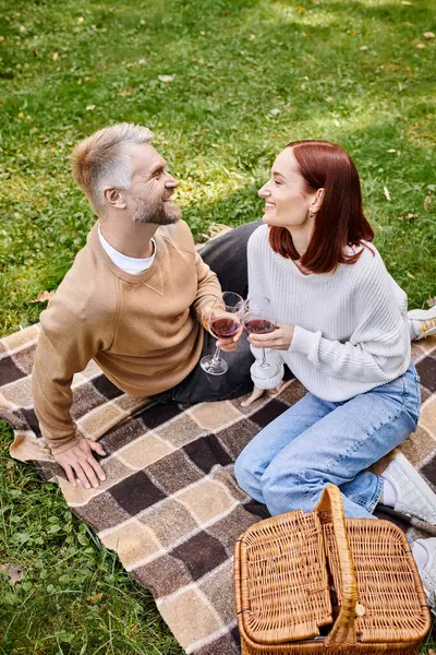 Paar genießt ein Picknick, hält Weingläser auf einer Decke. — Stockfoto