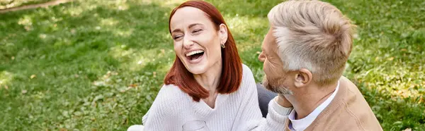 Un uomo e una donna ridono felici mentre si godono la compagnia in un campo erboso. — Foto stock