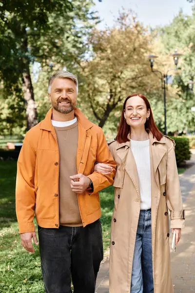 Adult couple in casual attire walk down a city sidewalk on a sunny day. — Stock Photo