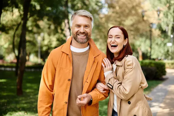 A man and a woman in casual attire walk together in a tranquil park setting. — Stock Photo