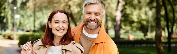 A man and woman in casual attire pose affectionately for a picture in a park. — Stock Photo