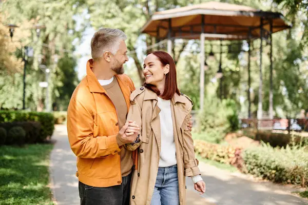 Adult loving couple in casual attires enjoying a leisurely walk in the park. — Stock Photo