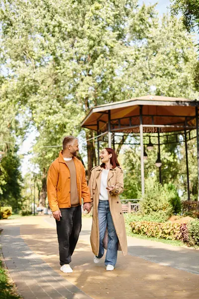 A man and a woman walk hand in hand down a scenic path in a park. — Stock Photo