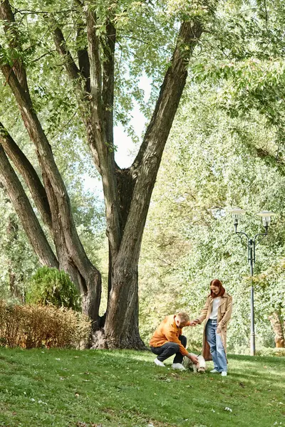 Una pareja en atuendo casual de pie juntos en un parque cubierto de hierba. - foto de stock