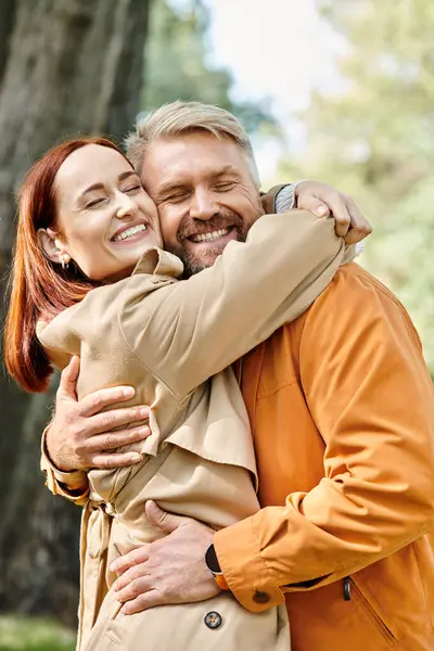 A loving couple in casual attire warmly hugging each other in a serene park setting. — Stock Photo