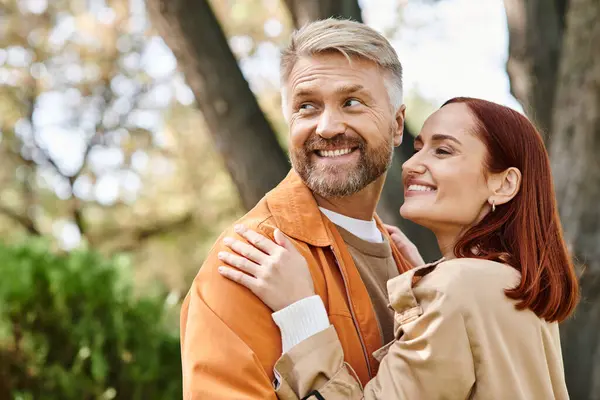 A man and a woman happily smiling at the camera during a walk in the park. — Stock Photo