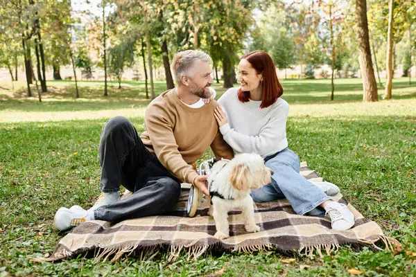 A man and woman sit on a blanket with their dog. — Stock Photo