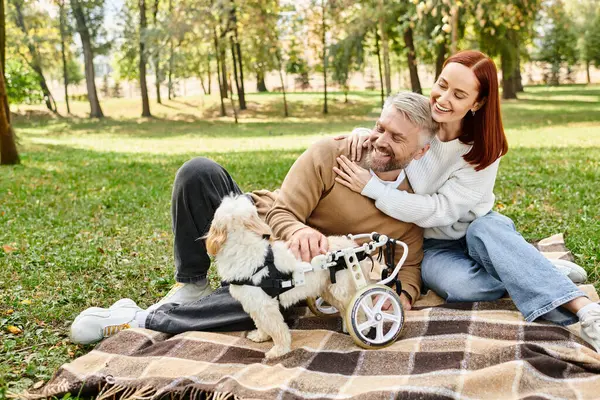 A man and woman relax on a blanket with their dog in a serene park. — Stock Photo