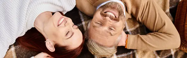 A man and a woman peacefully laying on a blanket in a park. — Stock Photo