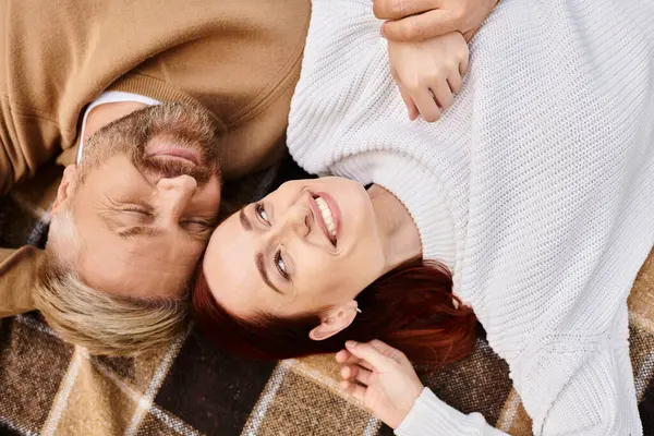 A man and woman in casual attire are peacefully laying together on a plaid blanket. — Stock Photo