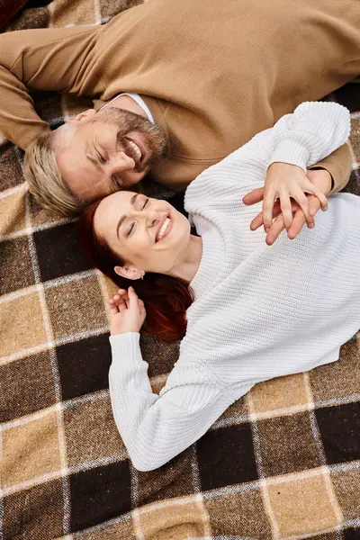 Un homme et une femme reposent paisiblement sur une couverture dans un parc. — Photo de stock