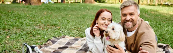 Un homme et une femme profitent d'un moment paisible sur une couverture avec leur chien dans un parc. — Photo de stock