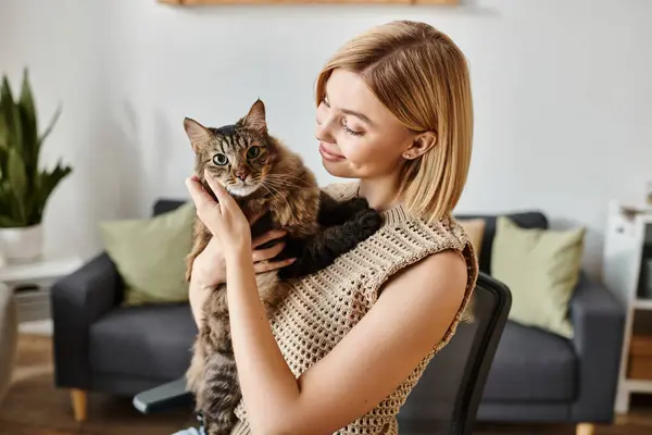 A woman with short hair sitting in a chair, peacefully holding a fluffy cat in her arms at home. — Stock Photo