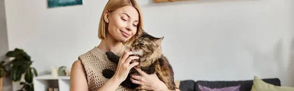 Una donna attraente con i capelli corti culla un gatto nelle sue mani, mostrando il legame tra umano e felino.. — Foto stock