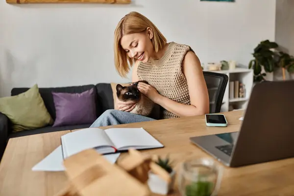 Donna dai capelli corti seduta su un divano, amorevolmente accarezzare un piccolo gatto. — Foto stock