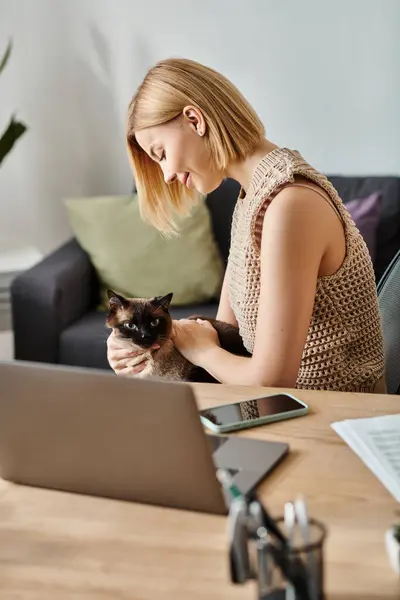 A stylish woman with short hair relaxes at a table with a content cat resting on her lap. — Stock Photo