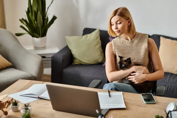 A stylish woman with short hair sitting on a couch, lovingly holding her cat close in a cozy home setting. — Stock Photo