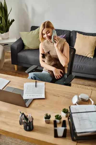 A woman with short hair sits on a couch, lovingly holding her cat in a warm embrace. — Stock Photo