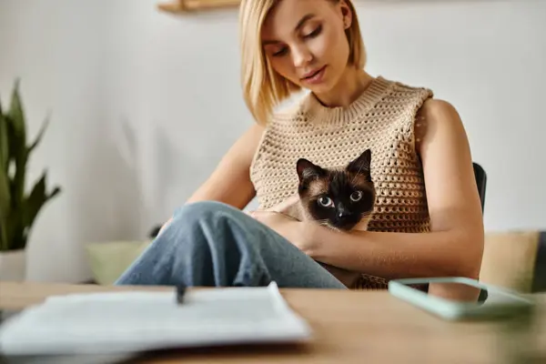 Short-haired woman sitting at table with content tabby cat on her lap, sharing a peaceful moment at home. — Stock Photo