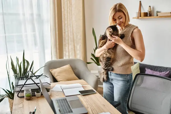 A woman with short hair gently holds a cat in her hands, showcasing a moment of connection and comfort at home. — Stock Photo