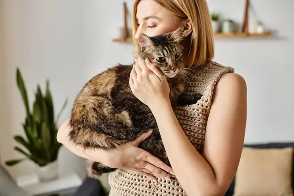 A woman with short hair is lovingly holding her cat in her arms at home, displaying a deep bond between them. — Stock Photo