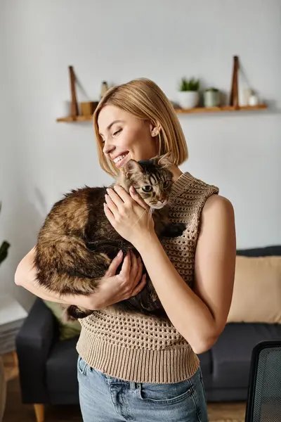 A woman with short hair peacefully cradling a cat in her arms at home, sharing a moment of love and bond. — Stock Photo