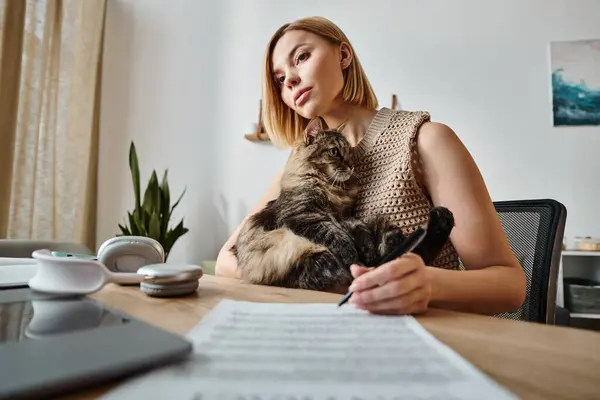 Uma mulher de cabelos curtos sentada em uma mesa, engajando-se com seu gato em um ambiente acolhedor casa. — Fotografia de Stock