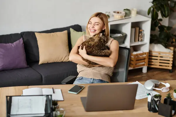 Mulher de cabelos curtos sentada na mesa, carinhosamente embalando um gato fofo. — Fotografia de Stock