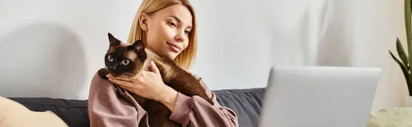Una donna con i capelli corti si rilassa su un divano, abbracciando pacificamente il suo gatto in un momento accogliente a casa. — Foto stock