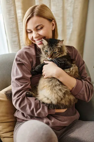 A woman with short hair peacefully sits on a couch while holding her cat, sharing a moment of affection and contentment. — Stock Photo