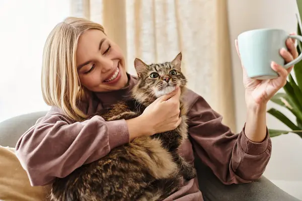 A woman with short hair sitting on a couch, holding her cat with a serene expression. — Stock Photo
