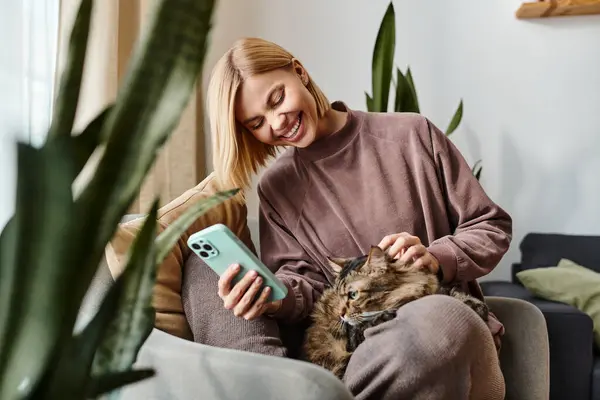 A woman with short hair is sitting on a couch, gently holding a cat in her arms, showing affection and enjoying a peaceful moment together. — Stock Photo