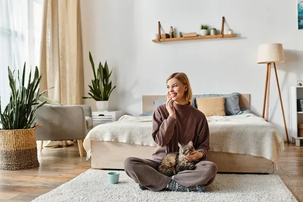 Eine bezaubernde Frau mit kurzen Haaren sitzt zu Hause liebevoll neben ihrer katzenhaften Gefährtin auf dem Boden. — Stock Photo