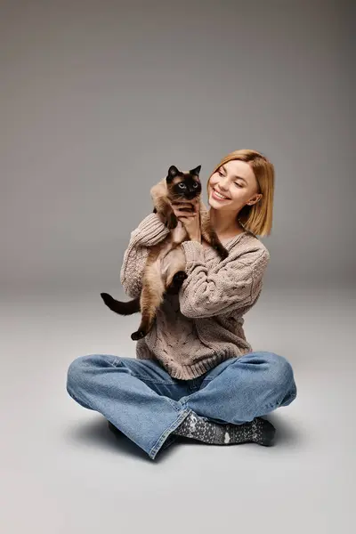 Uma mulher com cabelo curto encontra paz enquanto está sentada no chão e segurando seu amado gato em seus braços. — Fotografia de Stock