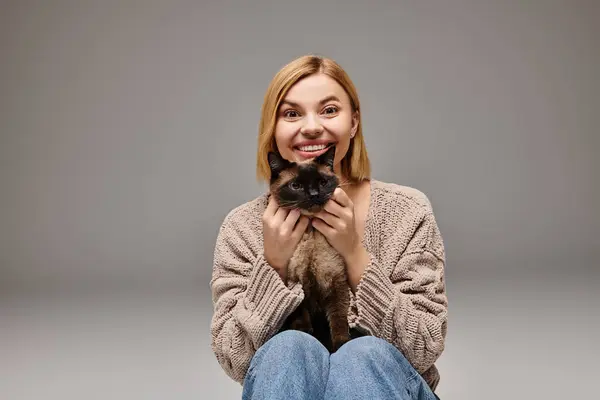 Uma mulher cativante com cabelo curto senta-se no chão, segurando seu amado gato, compartilhando um momento tranquilo em casa. — Fotografia de Stock