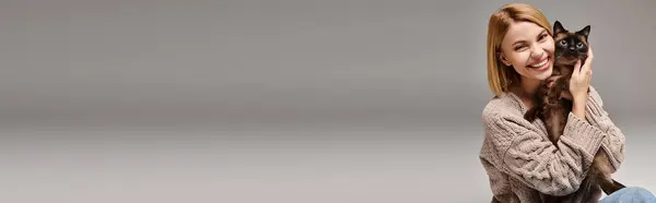 Стильная женщина с короткими волосами мирно сидит на полу, нежно держа любимого кота дома. — стоковое фото