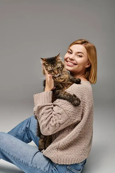 Serene woman with short hair sits on floor, tenderly holds her cat close in a cozy home setting. — Stock Photo