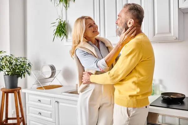Ein reifes Liebespaar in gemütlicher Hausmannskleidung steht zusammen in der Küche und genießt die schöne Zeit miteinander. — Stockfoto