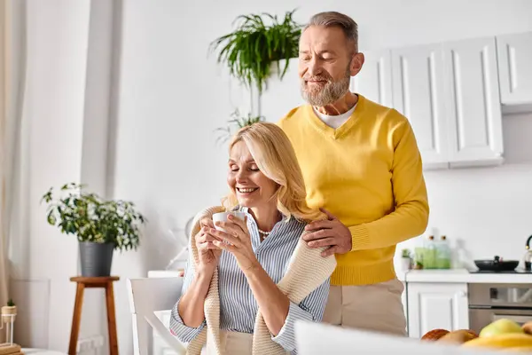 A mature loving couple in cozy homewear stands side by side in a kitchen, sharing a moment of togetherness. — Stock Photo