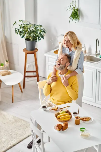 Un uomo seduto su una sedia tiene teneramente una donna, incarnando amore e insieme in un ambiente accogliente casa. — Foto stock